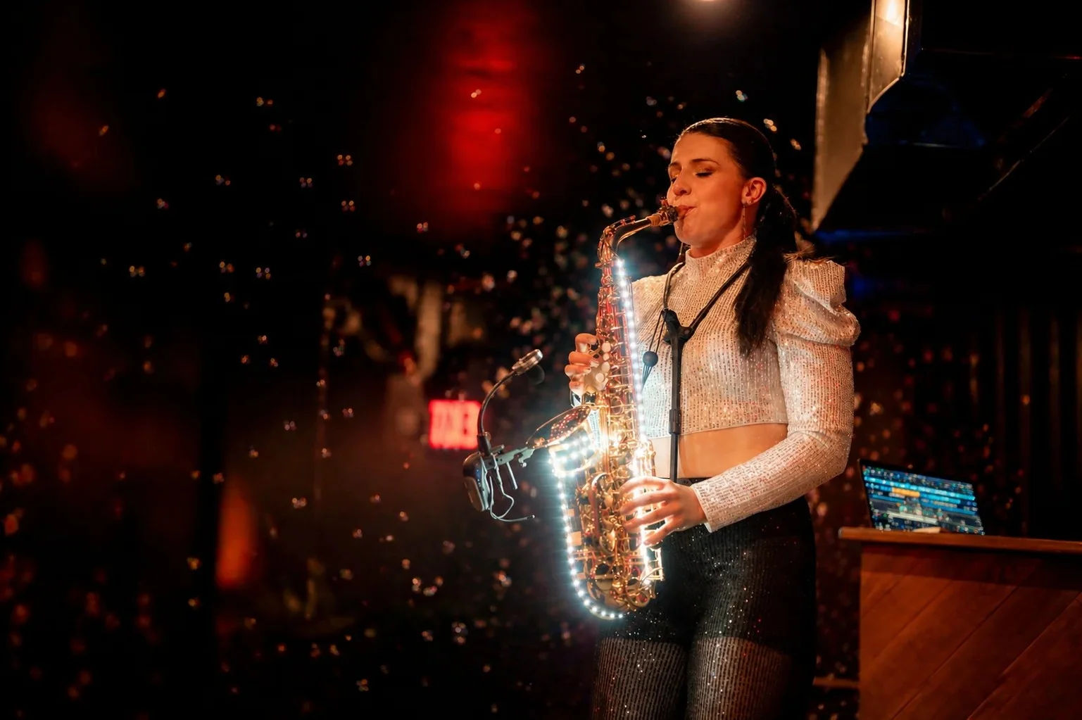 Saxophone artist performing under stage lighting at a New York venue